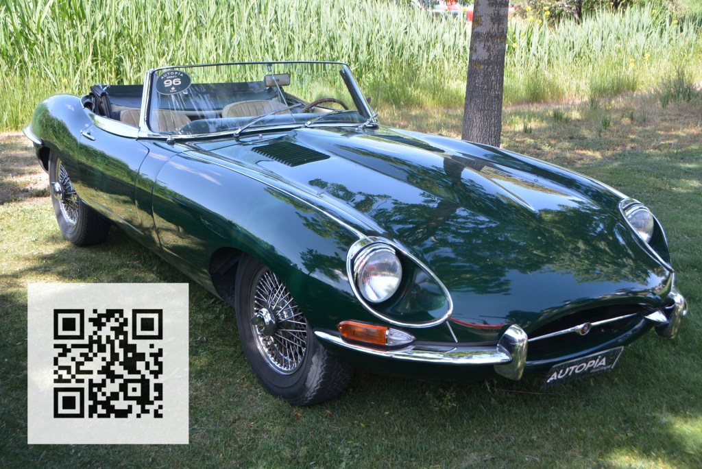A classic green convertible car parked on grass, featuring chrome details and wire-spoke wheels. A QR code is visible in the bottom left corner.