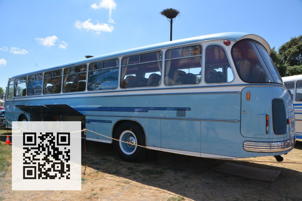 Side view of a vintage blue bus parked outdoors with a clear blue sky and a QR code in the foreground.